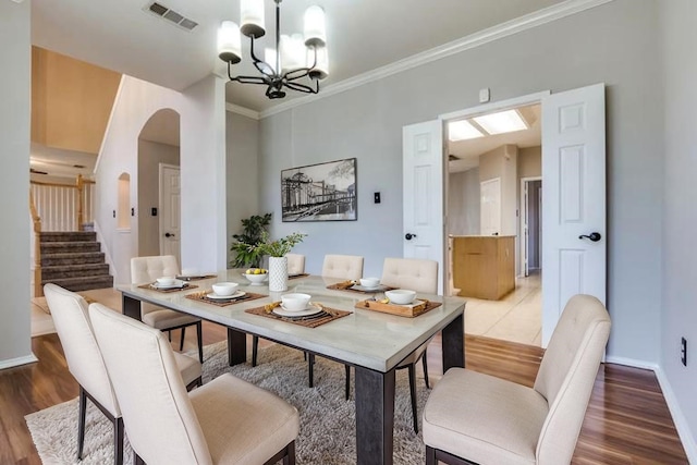 1403 Bosher Dr, Cedar Hill, TX 75104 - dining room featuring a chandelier, arched walkways, crown molding, light wood-style floors, and stairs