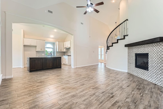 140 Godstone Ln, Prosper, TX 75078 - unfurnished living room with light wood-type flooring, high vaulted ceiling, a ceiling fan, arched walkways, and stairway