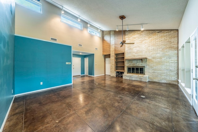 4524 Coyote Pt, Denton, TX 76208 - unfurnished living room featuring track lighting, a ceiling fan, a towering ceiling, a fireplace, and a textured ceiling