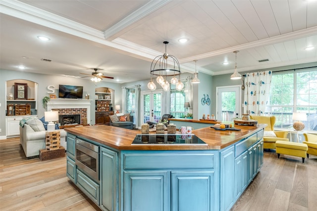 200 Stone Hollow Ct, Prosper, TX 75078 - kitchen with butcher block countertops, blue cabinetry, stainless steel microwave, black electric cooktop, and ornamental molding