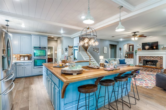 200 Stone Hollow Ct, Prosper, TX 75078 - kitchen with butcher block counters, blue cabinetry, stainless steel appliances, open floor plan, and light wood-type flooring