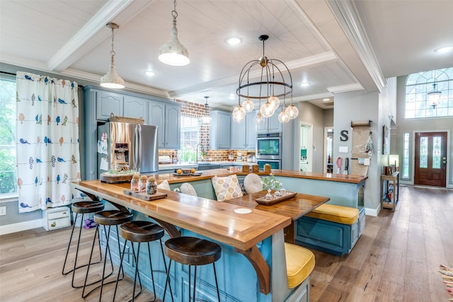 200 Stone Hollow Ct, Prosper, TX 75078 - kitchen with stainless steel appliances, crown molding, blue cabinets, butcher block countertops, and light wood finished floors