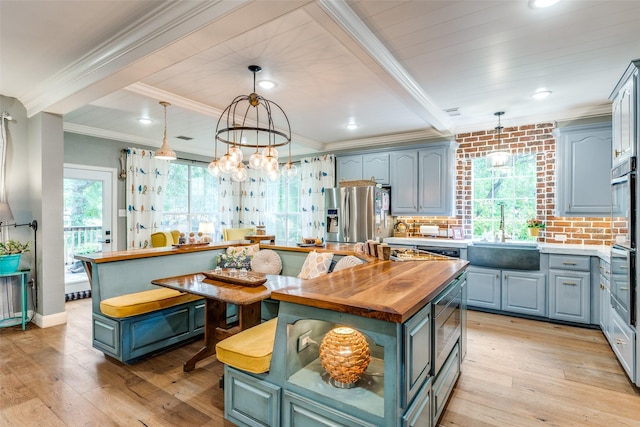 200 Stone Hollow Ct, Prosper, TX 75078 - kitchen featuring butcher block counters, appliances with stainless steel finishes, a center island, light wood-style floors, and ornamental molding