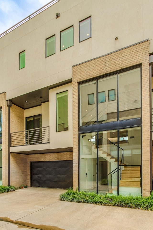1847 Summit Ave Unit 2B, Dallas, TX 75206 - back of property featuring stucco siding, brick siding, an attached garage, and driveway