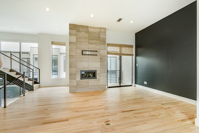 1847 Summit Ave Unit 2B, Dallas, TX 75206 - unfurnished living room featuring light wood-type flooring, recessed lighting, stairs, and a tile fireplace