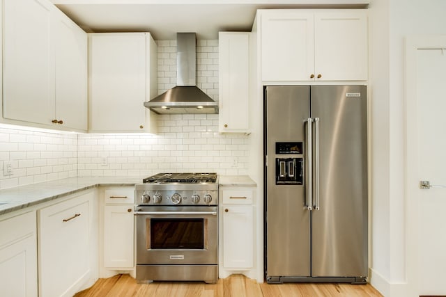 1847 Summit Ave Unit 2B, Dallas, TX 75206 - kitchen with premium appliances, wall chimney range hood, white cabinets, light stone countertops, and light wood-style floors