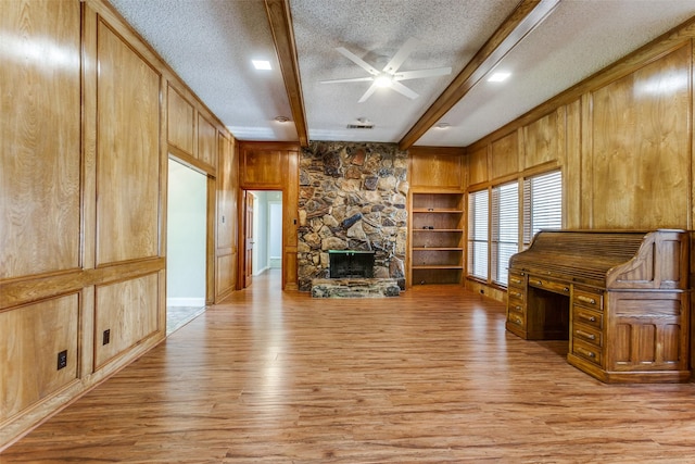5008 Natchez Dr, Sachse, TX 75048 - unfurnished living room featuring light wood-type flooring, beam ceiling, ceiling fan, a textured ceiling, and wooden walls