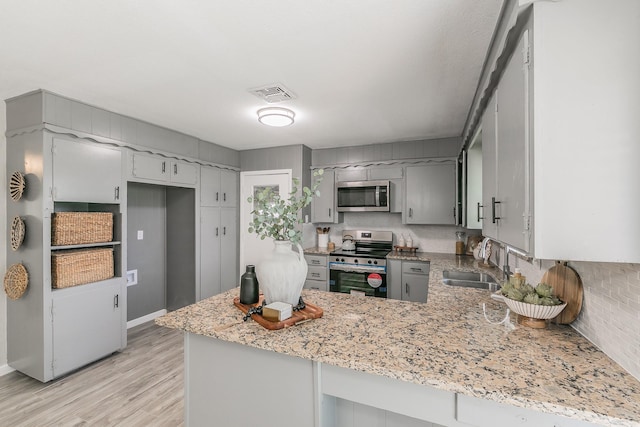 5909 Eisenhower Dr, Fort Worth, TX 76112 - kitchen featuring stainless steel appliances, gray cabinets, a peninsula, light wood-type flooring, and a warming drawer
