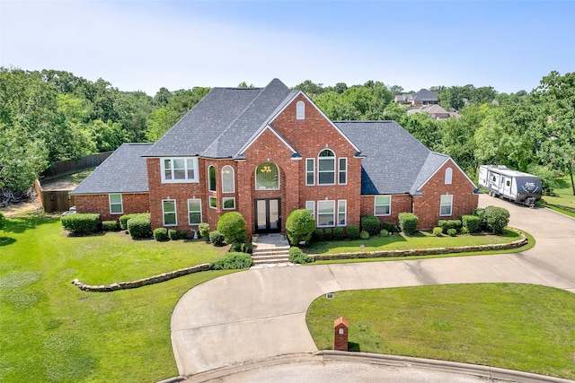 2104 Turtlecreek, Denison, TX 75020 - view of front of home with curved driveway, a shingled roof, brick siding, and a front lawn