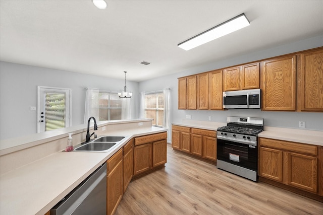 1205 Bonnet Dr, Fort Worth, TX 76131 - kitchen with appliances with stainless steel finishes, brown cabinets, a chandelier, and light wood-style flooring
