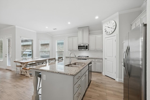 824 10th St, Argyle, TX 76226 - kitchen featuring appliances with stainless steel finishes, ornamental molding, light wood finished floors, a kitchen breakfast bar, and backsplash