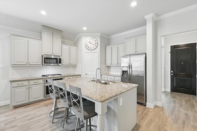 824 10th St, Argyle, TX 76226 - kitchen featuring appliances with stainless steel finishes, a center island with sink, ornamental molding, backsplash, and a kitchen bar