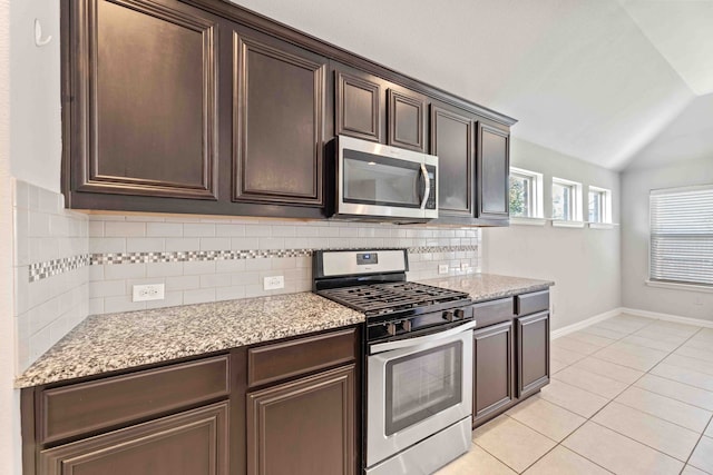 1033 Water Garden Cir, Little Elm, TX 75068 - kitchen featuring appliances with stainless steel finishes, vaulted ceiling, dark brown cabinets, decorative backsplash, and light tile patterned floors