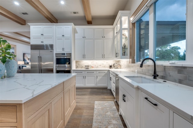 2110 Honey Ln, Celina, TX 75009 - kitchen featuring appliances with stainless steel finishes, beam ceiling, decorative backsplash, light wood-type flooring, and white cabinets