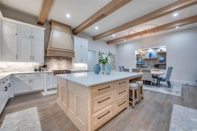 2110 Honey Ln, Celina, TX 75009 - kitchen with premium range hood, decorative backsplash, beam ceiling, a center island, and light stone countertops
