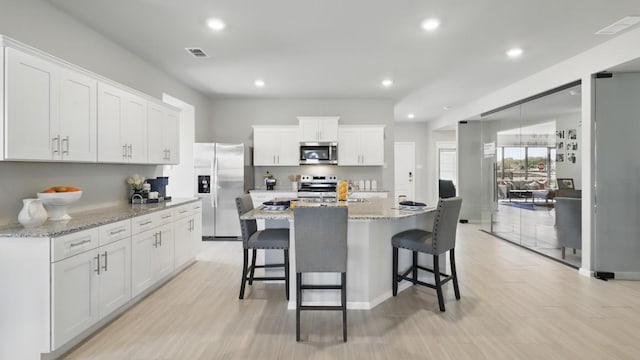 1517 Cansler Dr, Denton, TX 76249 - kitchen with appliances with stainless steel finishes, recessed lighting, a breakfast bar, white cabinets, and an island with sink
