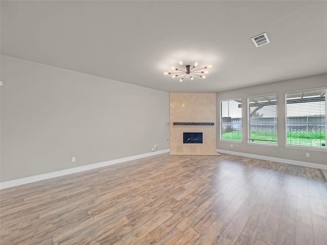 1034 Pelican Dr, Frisco, TX 75033 - unfurnished living room with wood finished floors, a chandelier, and a tile fireplace