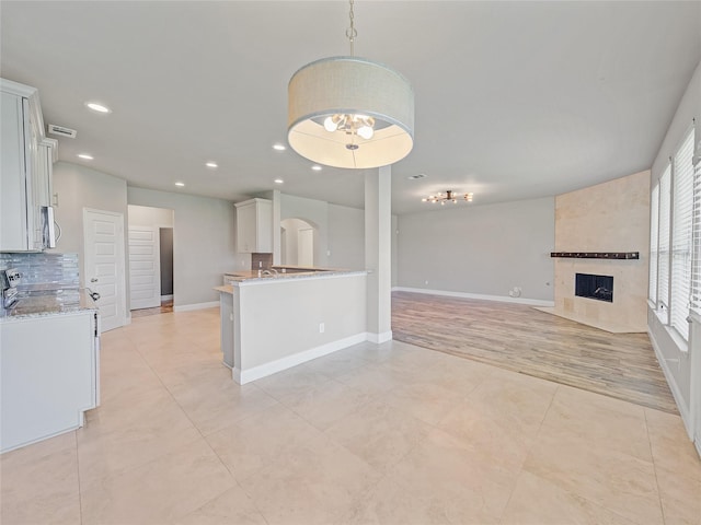 1034 Pelican Dr, Frisco, TX 75033 - kitchen featuring a fireplace, stainless steel microwave, recessed lighting, hanging light fixtures, and open floor plan