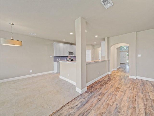 1034 Pelican Dr, Frisco, TX 75033 - kitchen with appliances with stainless steel finishes, arched walkways, white cabinets, light countertops, and recessed lighting