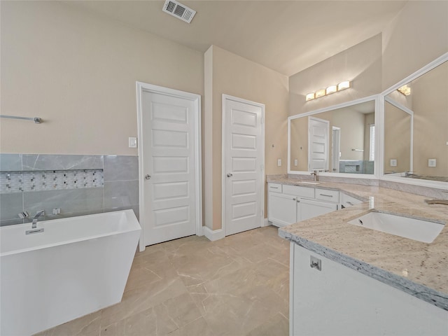 1034 Pelican Dr, Frisco, TX 75033 - bathroom featuring vanity, a freestanding tub, marble finish flooring, and tile walls