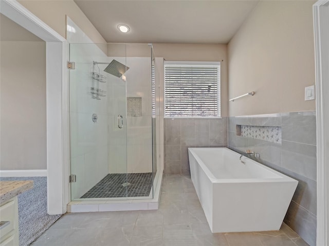 1034 Pelican Dr, Frisco, TX 75033 - bathroom featuring a freestanding bath, a stall shower, tile patterned floors, and tile walls
