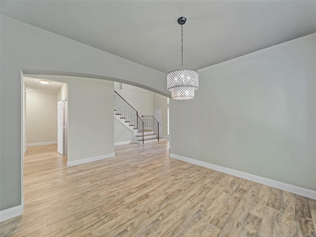 1034 Pelican Dr, Frisco, TX 75033 - empty room with light wood finished floors, arched walkways, stairway, and a chandelier