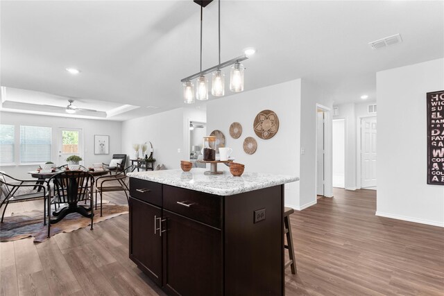 1105 Trace Dr, Aubrey, TX 76227 - kitchen with a kitchen bar, dark wood-style floors, a kitchen island, a ceiling fan, and hanging light fixtures