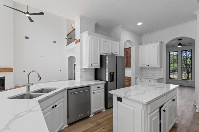 805 S Duncan Creek Ct, Weatherford, TX 76087 - kitchen featuring a ceiling fan, appliances with stainless steel finishes, arched walkways, crown molding, and light stone counters