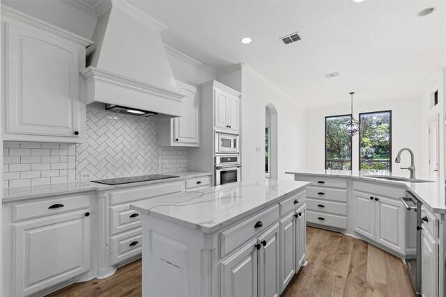 805 S Duncan Creek Ct, Weatherford, TX 76087 - kitchen featuring stainless steel appliances, custom range hood, light wood-style floors, a kitchen island, and arched walkways