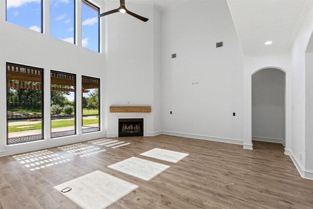 805 S Duncan Creek Ct, Weatherford, TX 76087 - unfurnished living room with arched walkways, a towering ceiling, wood finished floors, ceiling fan, and ornamental molding