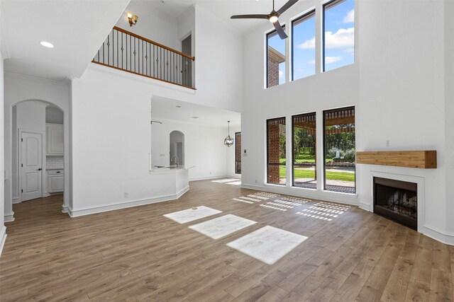 805 S Duncan Creek Ct, Weatherford, TX 76087 - unfurnished living room with crown molding, ceiling fan, arched walkways, wood finished floors, and a fireplace