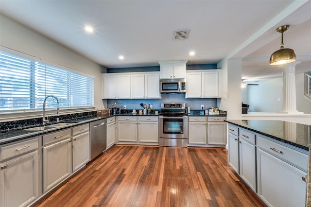 6318 White Oaks Ln, Frisco, TX 75035 - kitchen with appliances with stainless steel finishes, dark wood-style flooring, white cabinetry, decorative light fixtures, and dark stone counters