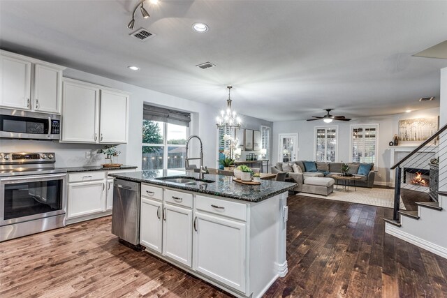 759 Bancroft Rd, Keller, TX 76248 - kitchen with appliances with stainless steel finishes, a kitchen island with sink, dark stone counters, dark wood-style flooring, and white cabinets