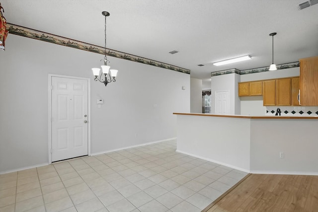 3516 San Patricio Dr, Plano, TX 75025 - kitchen with hanging light fixtures, a peninsula, brown cabinets, and a chandelier