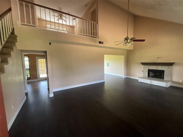 1705 Huntington Dr, Mesquite, TX 75149 - unfurnished living room with a ceiling fan, high vaulted ceiling, dark wood-type flooring, a fireplace with raised hearth, and stairs