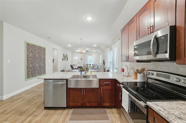 2409 Ross Ave, Fort Worth, TX 76164 - kitchen featuring appliances with stainless steel finishes, a peninsula, a chandelier, light wood-style floors, and light stone countertops