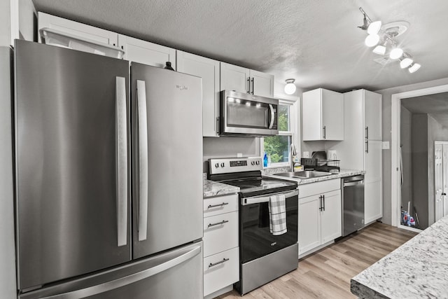 84 Kristin Dr, Pottsboro, TX 75076 - kitchen with appliances with stainless steel finishes, white cabinetry, light wood-style floors, a textured ceiling, and light stone countertops