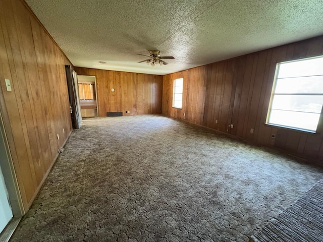 3560 Regal Rd, Fort Worth, TX 76111 - unfurnished living room featuring ceiling fan, wooden walls, a textured ceiling, and carpet floors