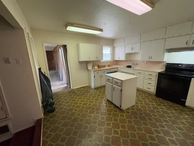 3560 Regal Rd, Fort Worth, TX 76111 - kitchen featuring electric range, light countertops, white cabinets, dark flooring, and a kitchen island
