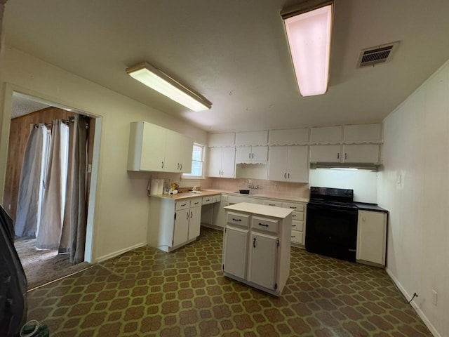 3560 Regal Rd, Fort Worth, TX 76111 - kitchen with black electric range, white cabinetry, under cabinet range hood, a kitchen island, and light countertops