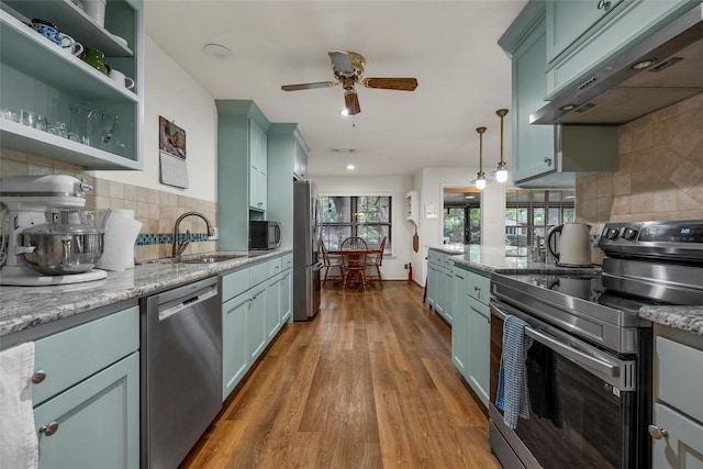 5512 Lake Charles Dr, Waco, TX 76710 - kitchen with stainless steel appliances, wall chimney exhaust hood, ceiling fan, decorative backsplash, and dark wood-type flooring