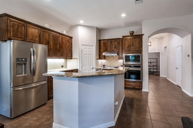 7601 Willowbend Dr, Mckinney, TX 75071 - kitchen featuring appliances with stainless steel finishes, arched walkways, dark tile patterned floors, backsplash, and recessed lighting