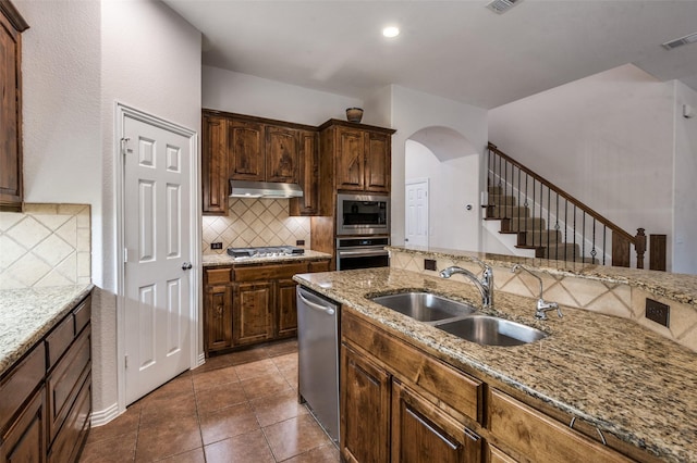 7601 Willowbend Dr, Mckinney, TX 75071 - kitchen with appliances with stainless steel finishes, under cabinet range hood, arched walkways, tasteful backsplash, and recessed lighting