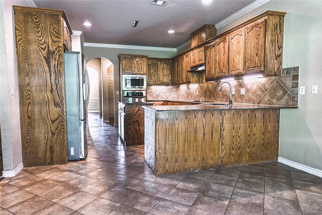104 Coldwater Creek Ln, Weatherford, TX 76088 - kitchen with appliances with stainless steel finishes, arched walkways, crown molding, tasteful backsplash, and a peninsula
