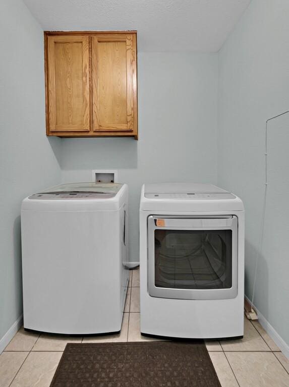 308 Greystone Dr, Lorena, TX 76655 - washroom featuring washing machine and dryer, cabinet space, and light tile patterned floors