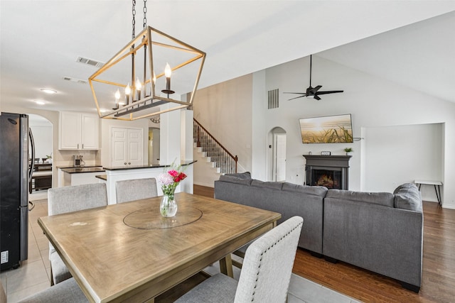 2708 Ferdinand, Grand Prairie, TX 75054 - dining space featuring arched walkways, stairway, a warm lit fireplace, a ceiling fan, and high vaulted ceiling