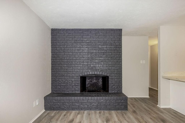 520 Hawthorne Dr, Allen, TX 75002 - unfurnished living room with wood finished floors, a brick fireplace, and a textured ceiling
