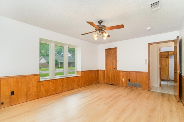 3004 Glasgow Dr, Arlington, TX 76015 - empty room featuring wood finished floors, a wainscoted wall, wooden walls, a ceiling fan, and a textured ceiling