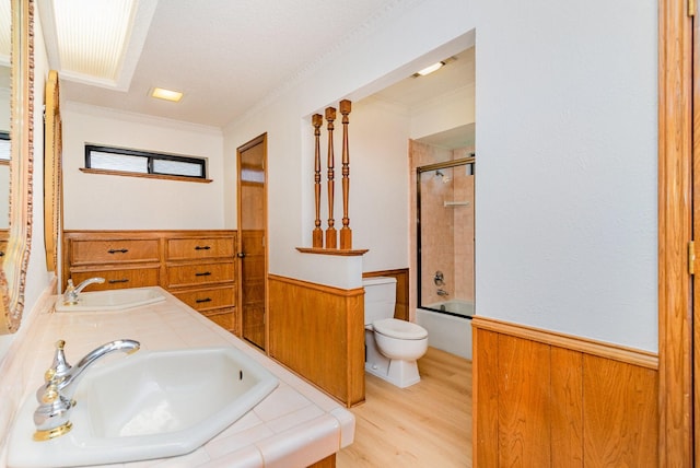 3004 Glasgow Dr, Arlington, TX 76015 - full bathroom with a wainscoted wall, wood finished floors, crown molding, shower / bath combination with glass door, and double vanity