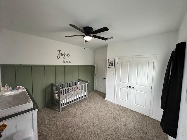2352 Wynchase Ln, Crandall, TX 75114 - carpeted bedroom featuring wainscoting, a decorative wall, a ceiling fan, a closet, and a crib